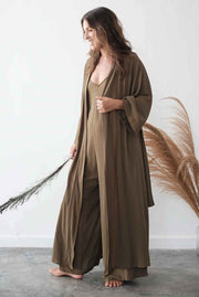 Woman wearing a long brown dress with a matching cardigan against a white background