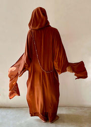 Person wearing a brown hooded garment against a plain background