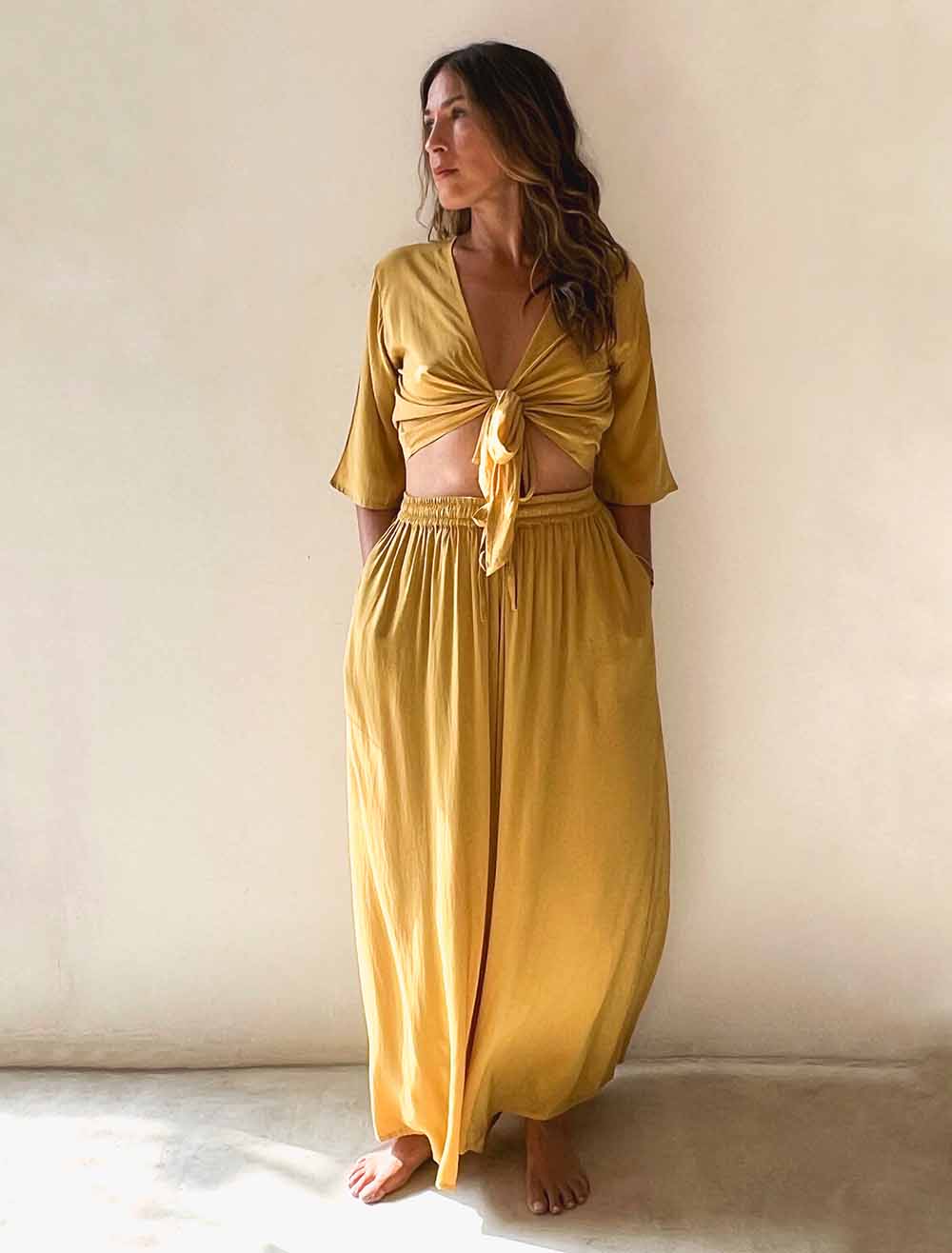 Woman wearing a mustard yellow outfit against a plain background