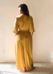 Person wearing a mustard yellow dress standing against a plain background
