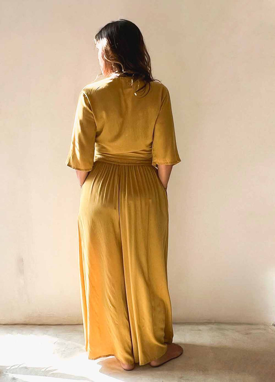 Person wearing a mustard yellow dress standing against a plain background