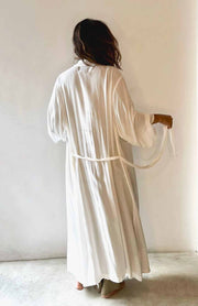 Person wearing a long white robe against a plain background