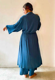 Woman wearing a blue dress standing against a plain background
