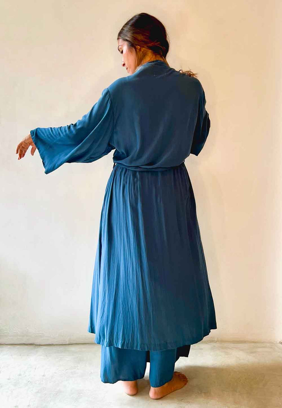 Woman wearing a blue dress standing against a plain background