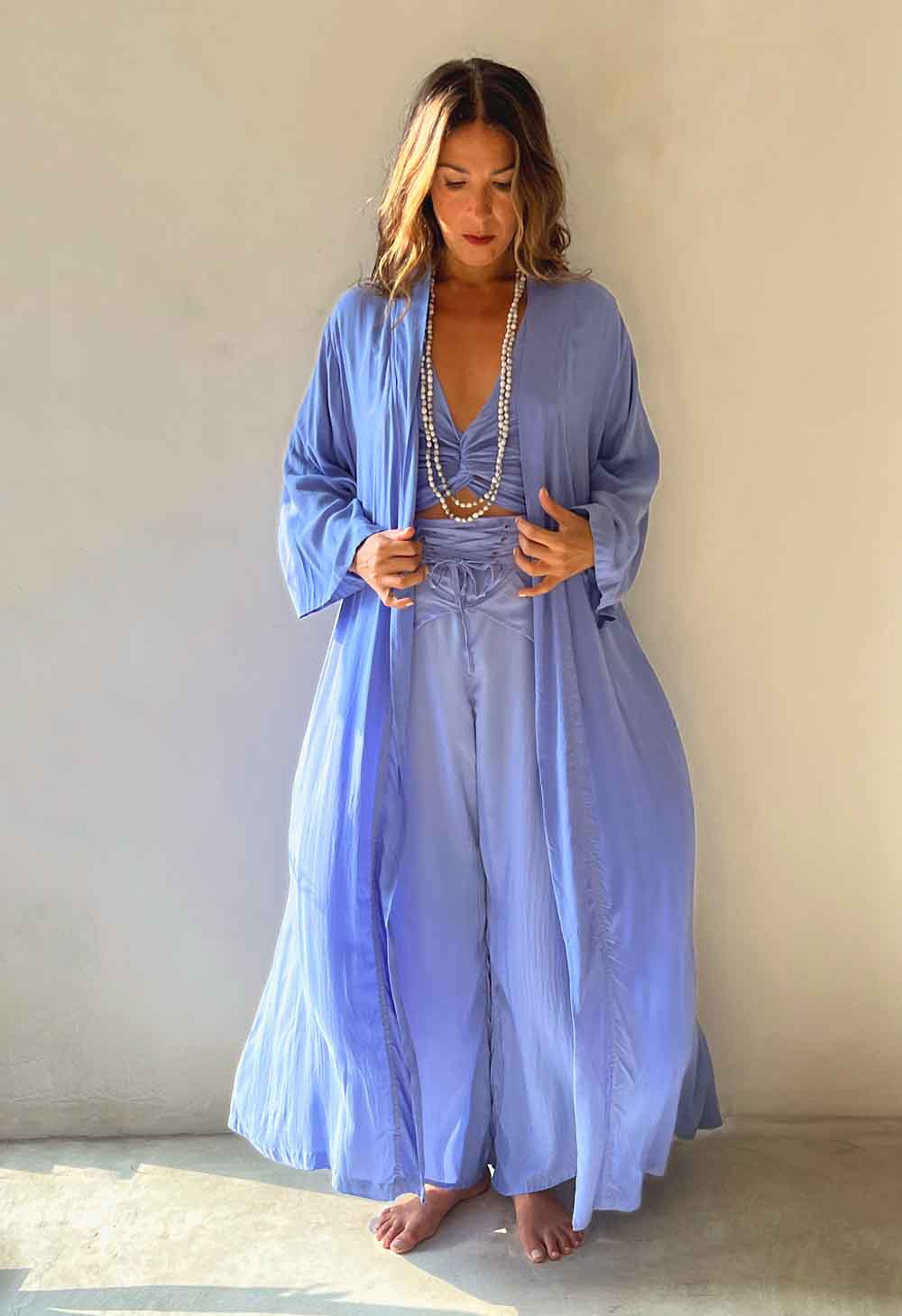 Woman wearing a long light blue robe against a plain background