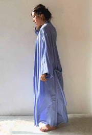 Person wearing a long light blue dress against a plain background