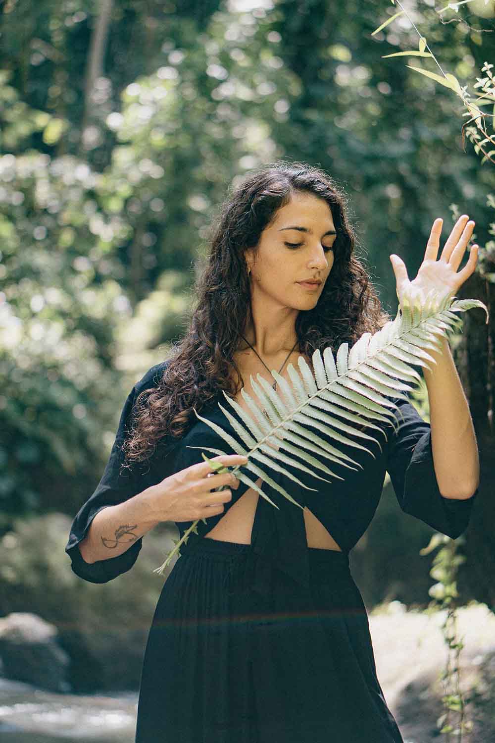Woman holding a large leaf in a forest setting