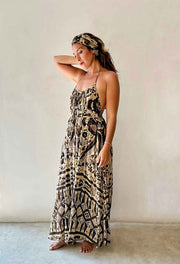 Woman wearing a long, patterned dress against a plain background