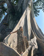 Person standing in front of a large tree with intricate carvings