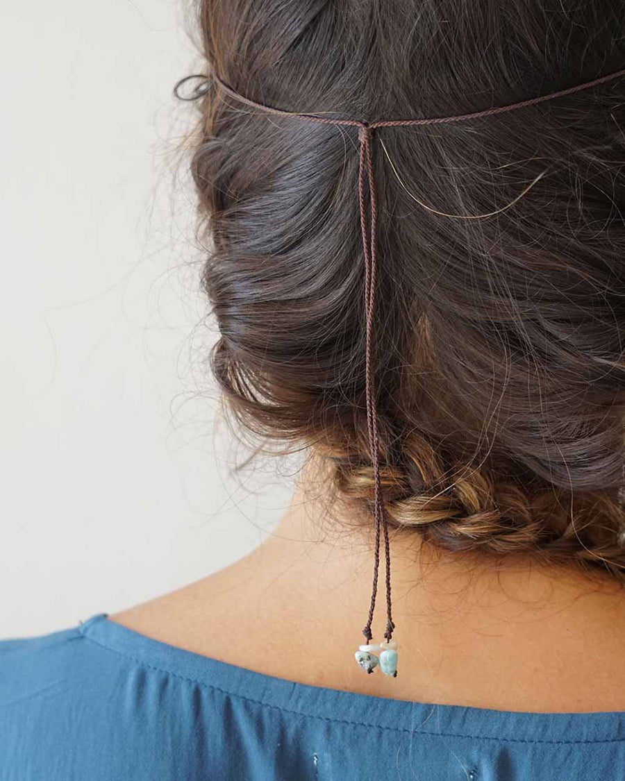 Person wearing a hair accessory with beads on a plain background
