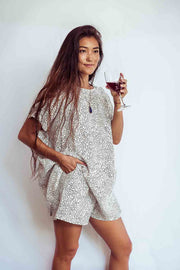 Woman in a patterned dress holding a glass of red wine against a white background