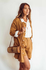 Woman wearing a brown outfit with a white shirt, holding a woven bag against a white background
