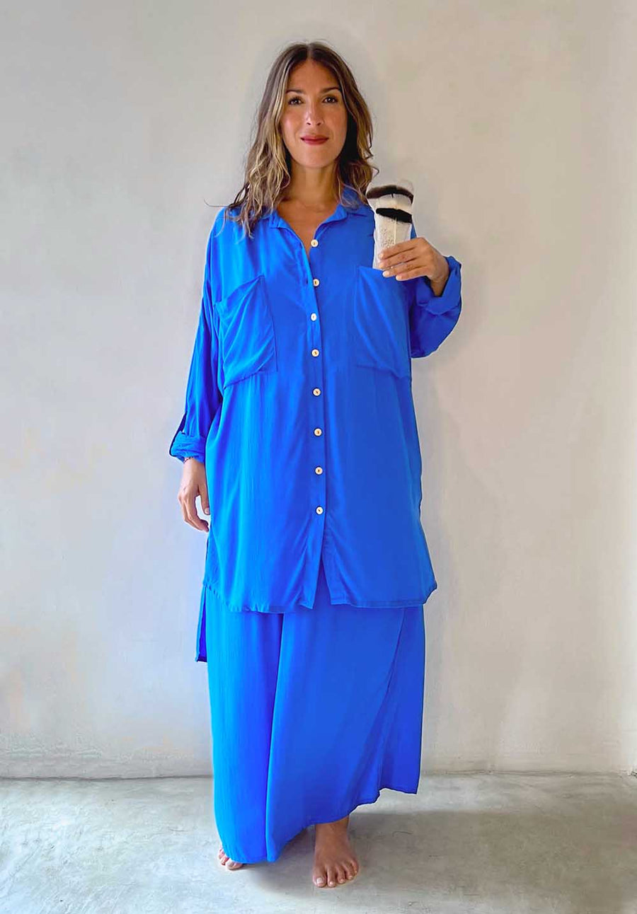 Woman wearing a blue outfit holding a coffee cup against a plain background