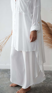 Person wearing a long white dress with a neutral background