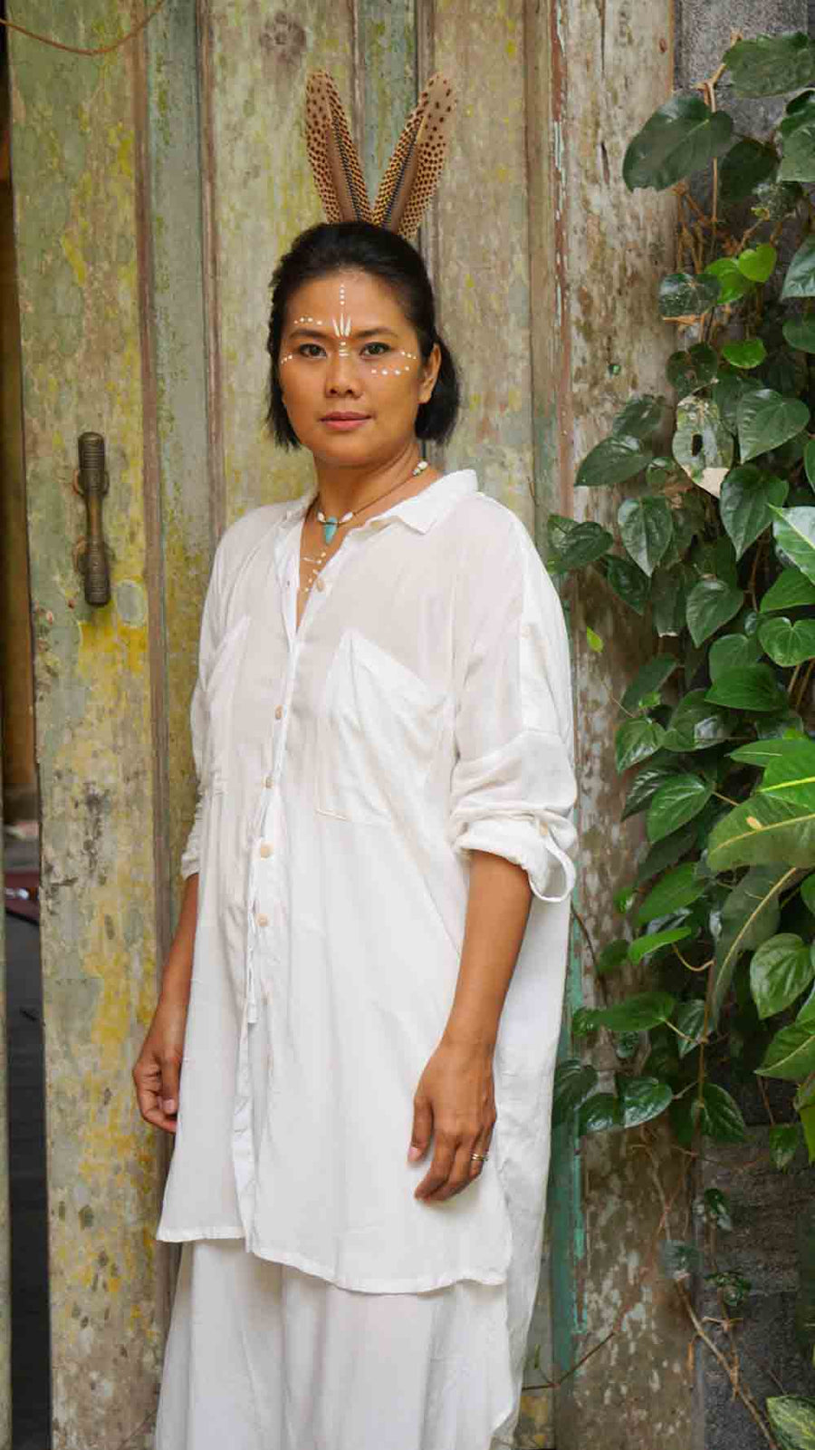 Person wearing a white outfit with decorative headband in an outdoor setting