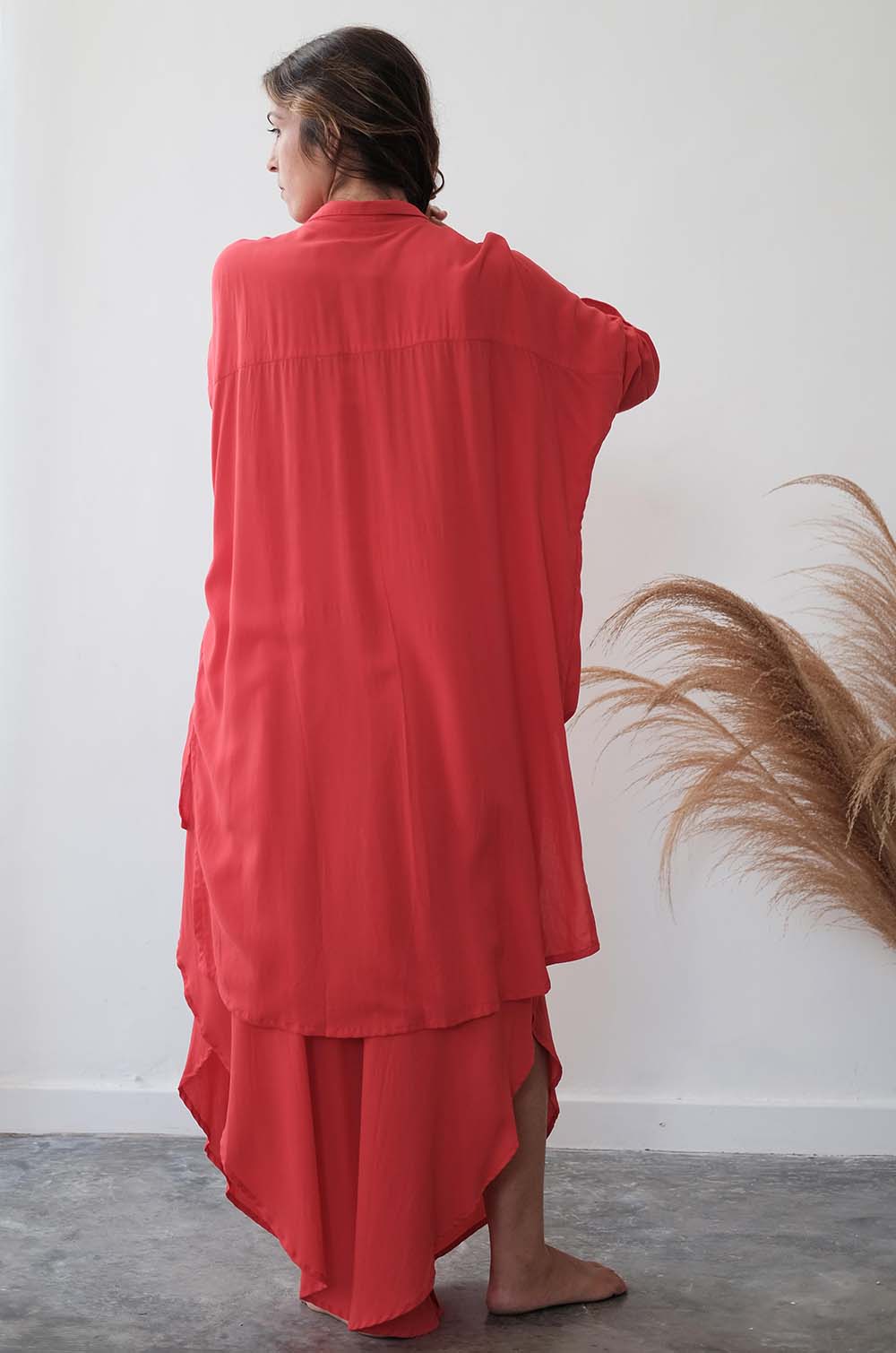 Person wearing a red outfit standing against a white wall with decorative elements.