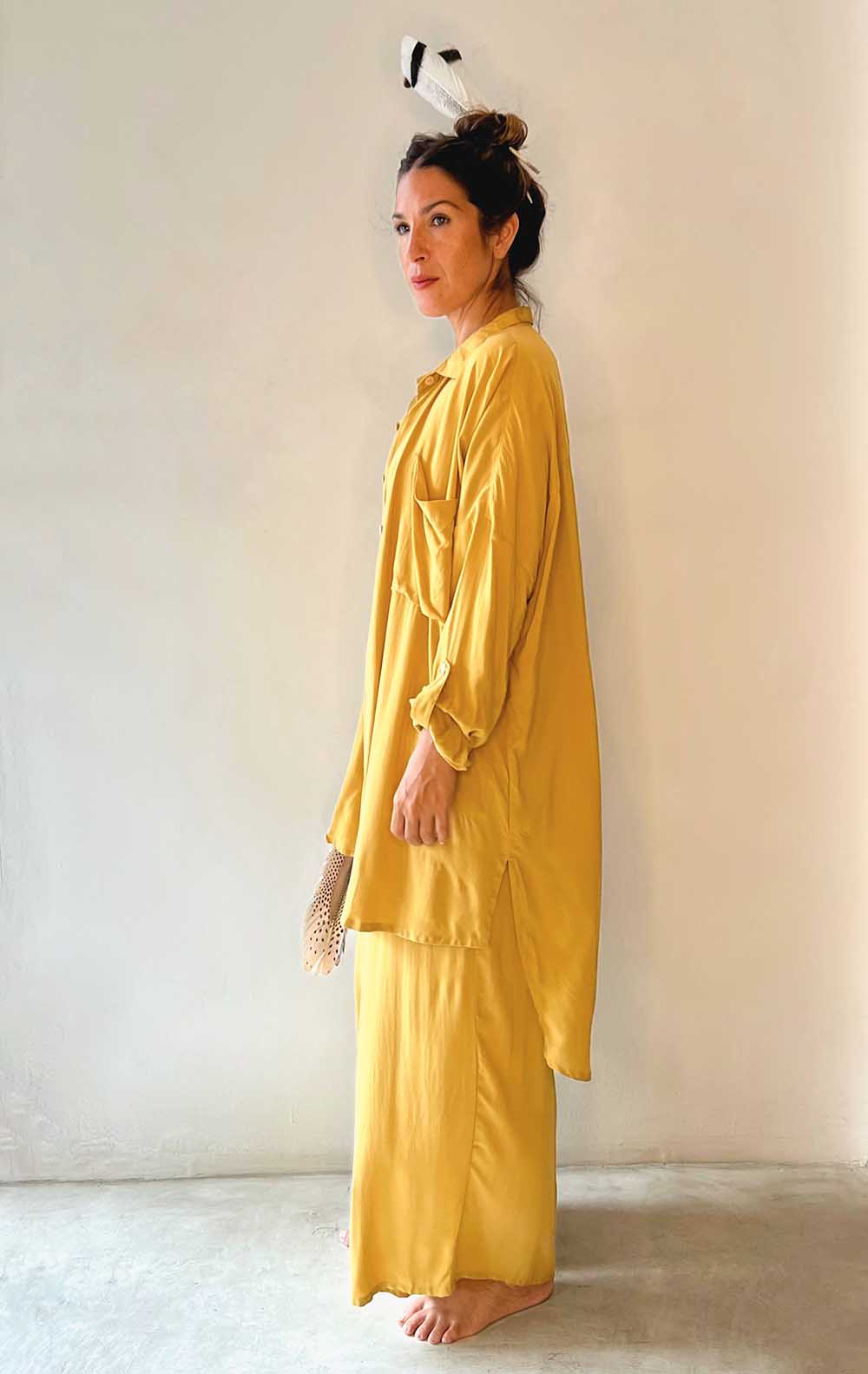 Woman wearing a yellow satin outfit against a plain background