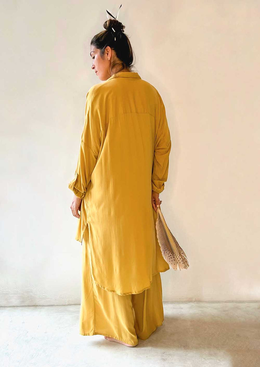 Person wearing a mustard yellow outfit against a plain background