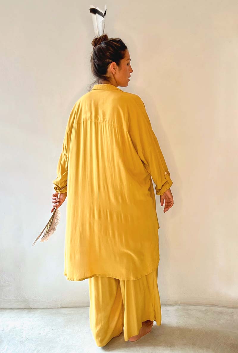 Woman wearing a yellow traditional outfit against a plain background