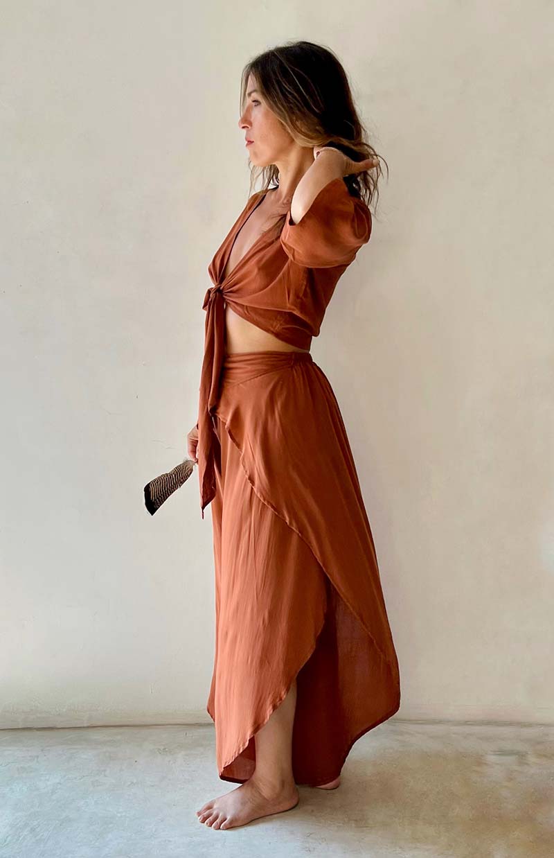 Woman wearing a brown outfit standing against a plain background