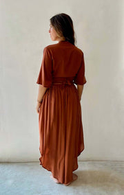 Woman wearing a rust-colored dress against a plain background