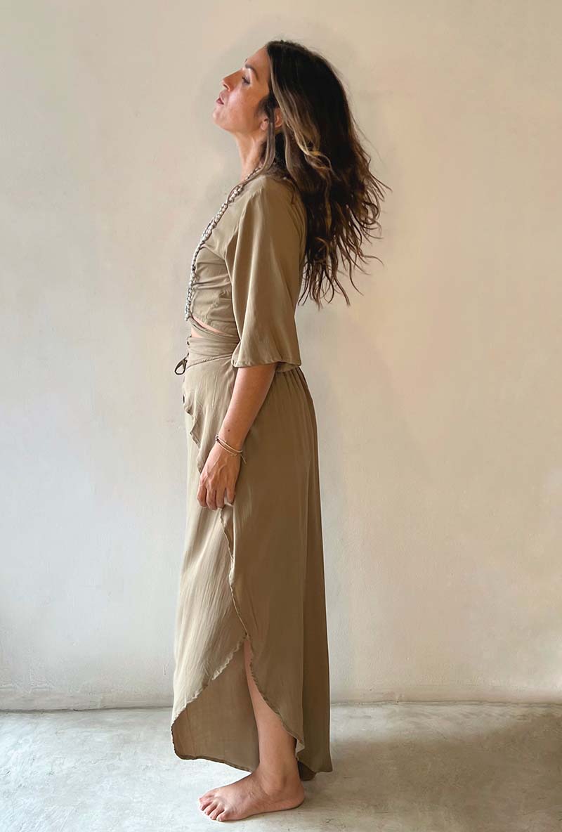 Woman wearing a long, light brown dress against a plain background