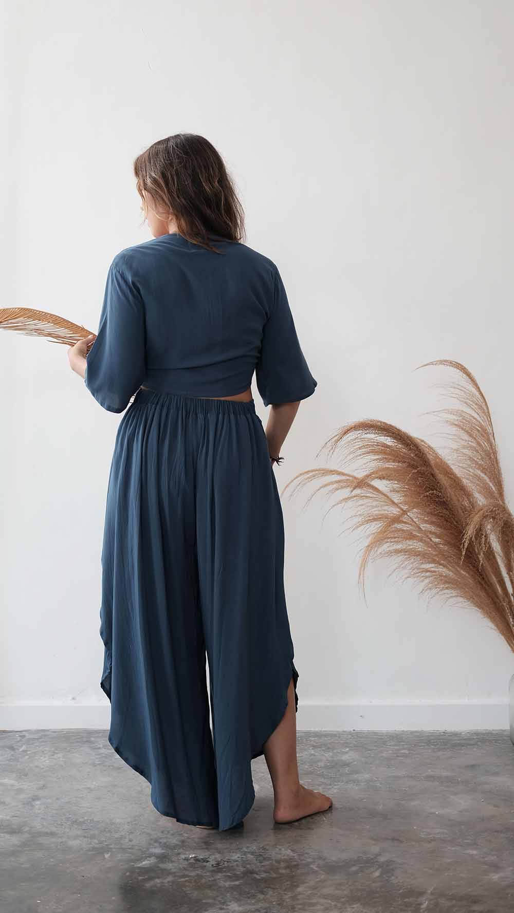 Person wearing a blue dress standing on a white floor with a feathered object nearby.