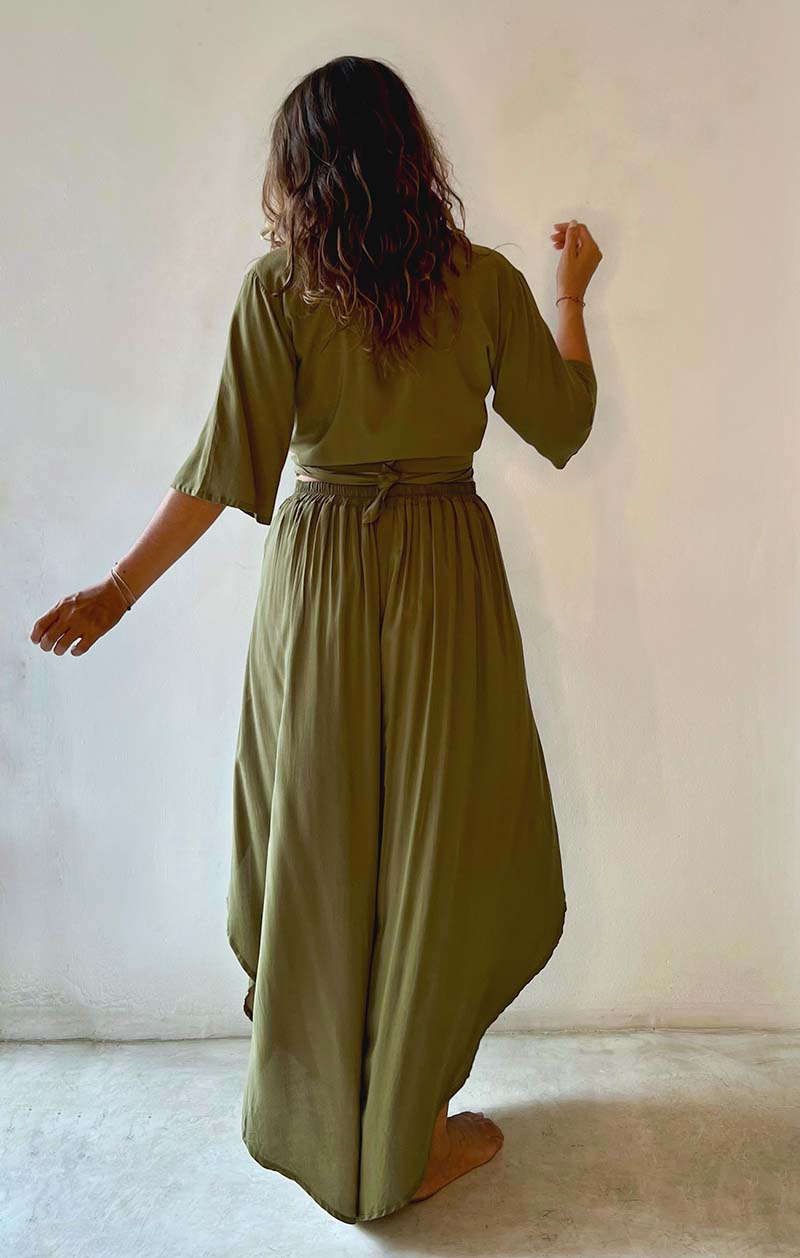 Person wearing a green dress standing against a white wall.