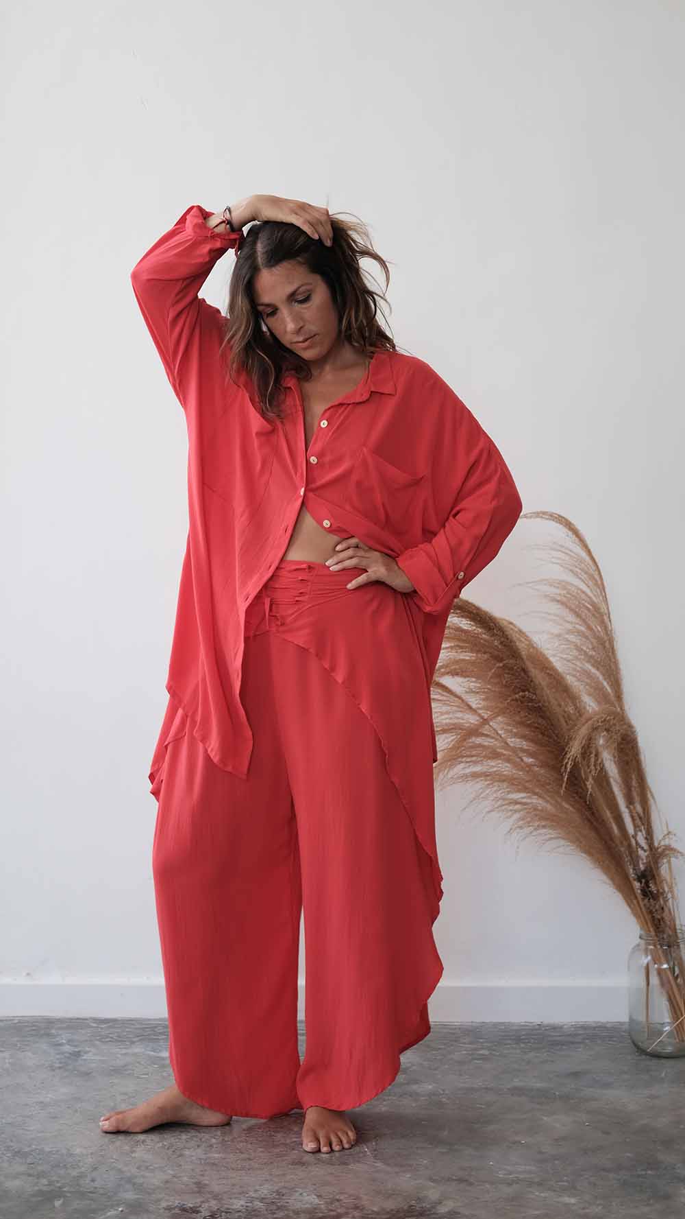 Woman wearing a red outfit standing against a white wall with decorative elements.