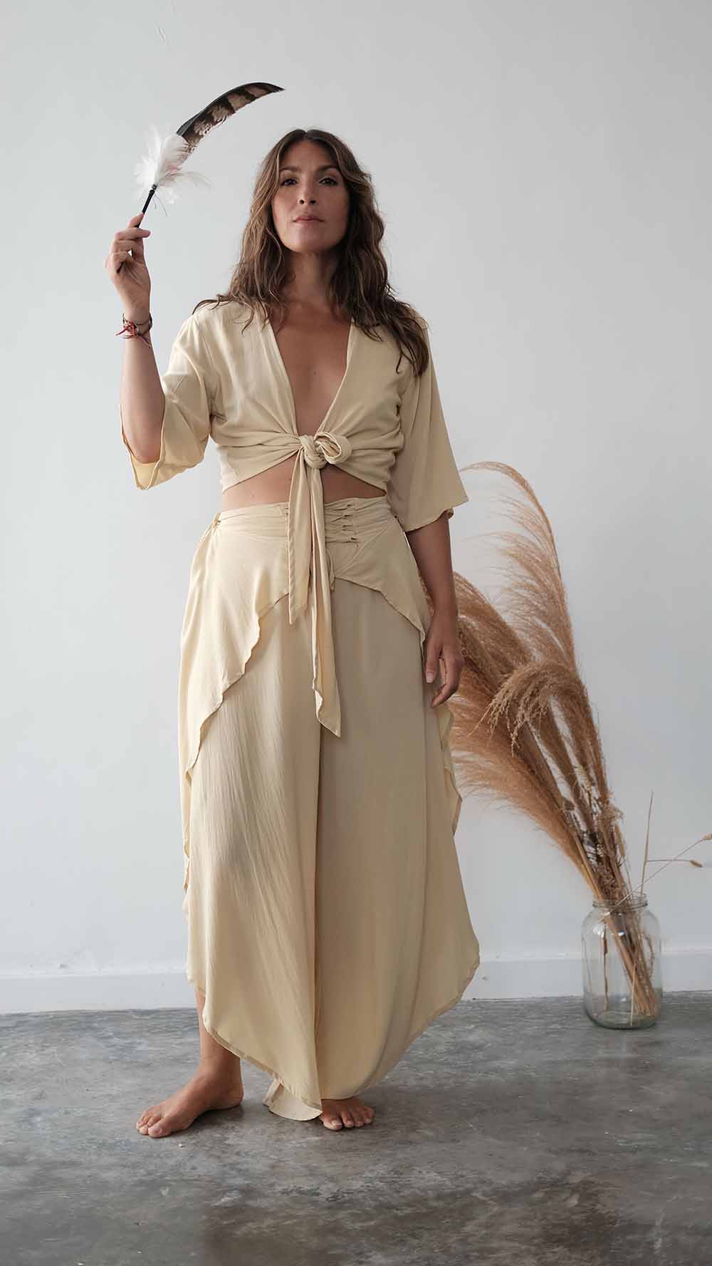Woman in a beige dress holding a broom against a white wall