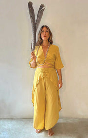 Woman in a yellow outfit holding a large decorative item against a plain background