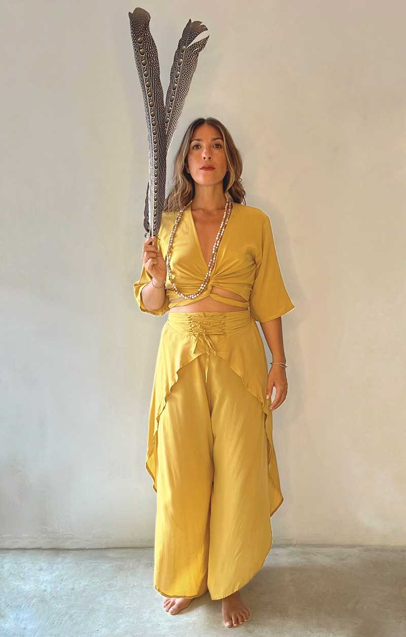 Woman in a yellow outfit holding a large decorative item against a plain background