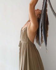 Woman in a long beige dress holding a piece of fabric against a plain background