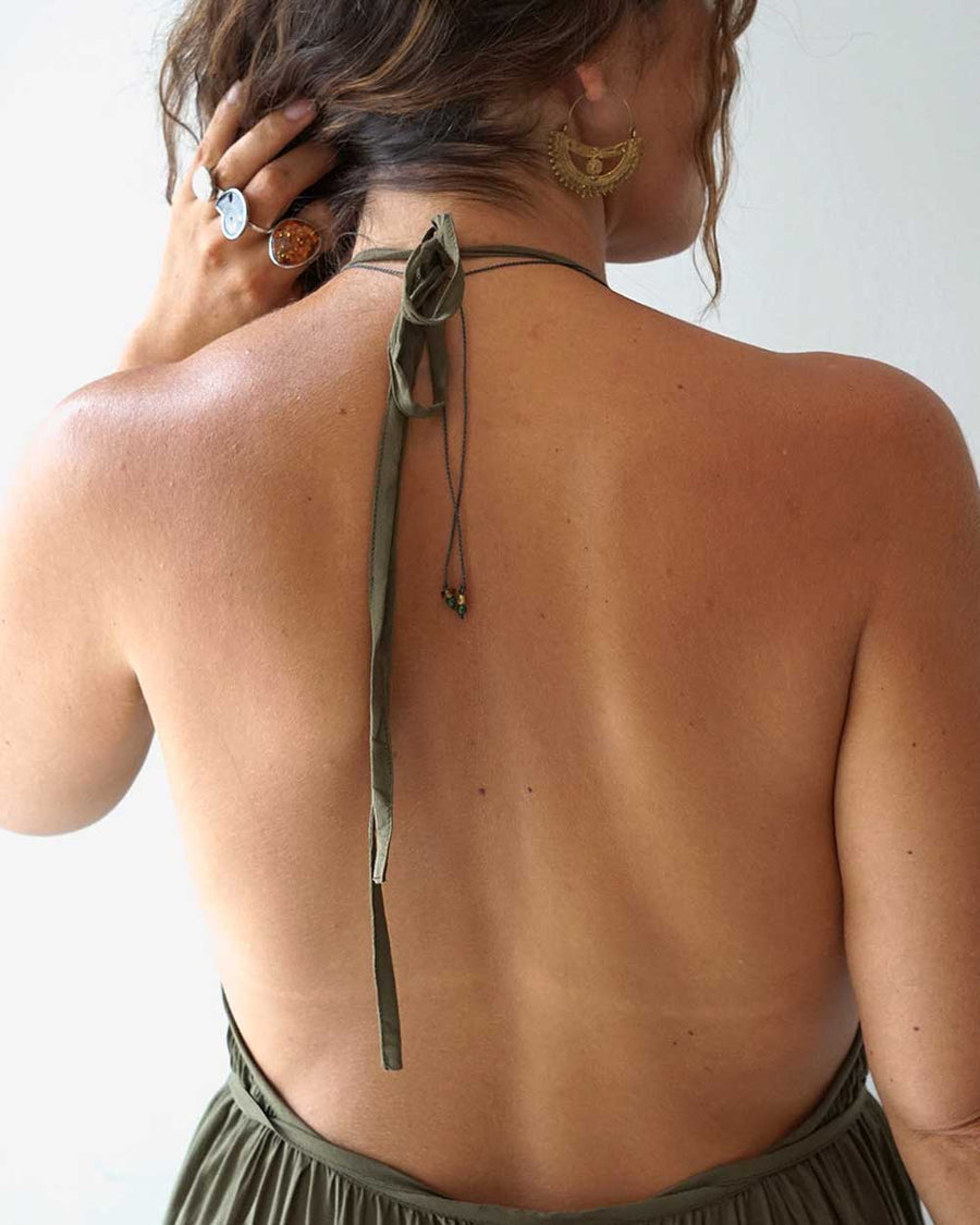 Person wearing a green halter top with a plain background