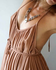 Brown dress with a necklace on a plain background