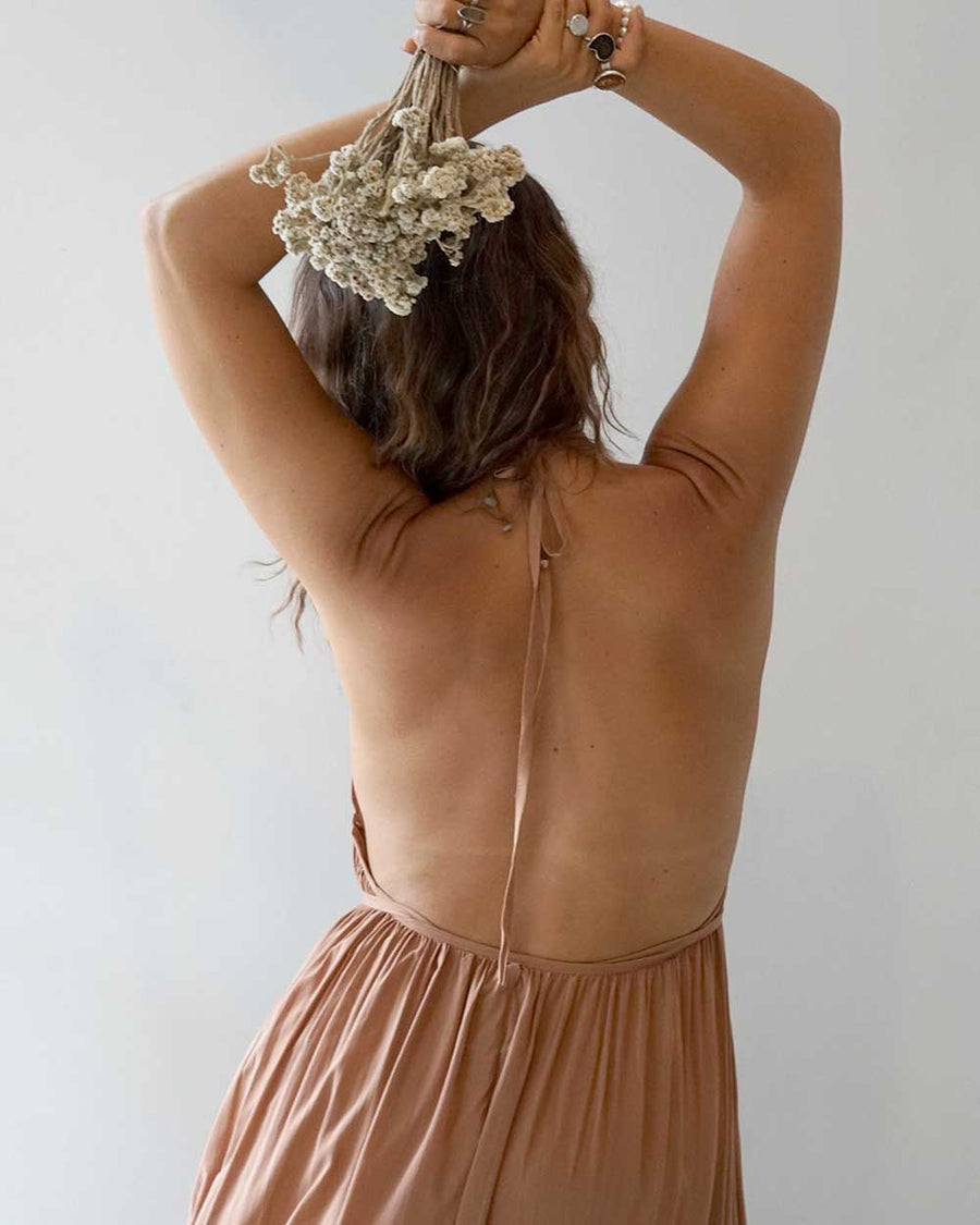 Woman in a brown dress holding dried flowers against a white background