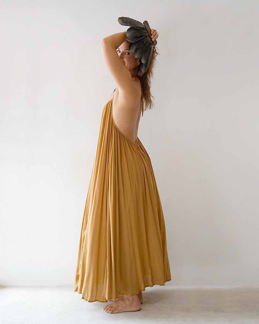 Woman wearing a mustard yellow dress against a white background