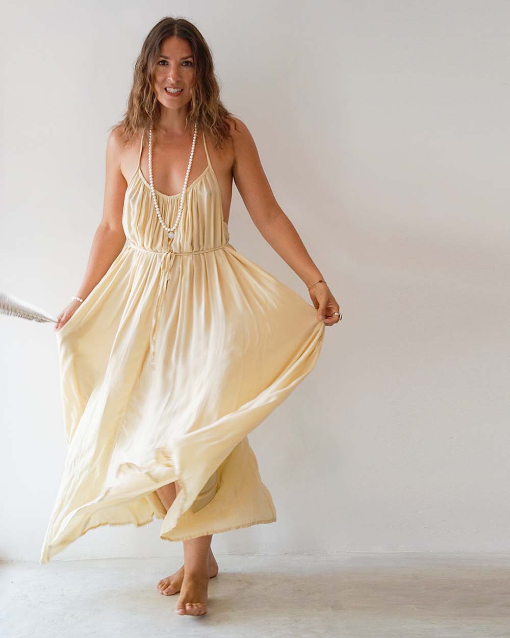 Woman wearing a flowing yellow dress against a plain background