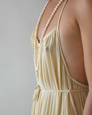 Beige dress with pearl straps on a plain background