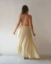 Woman wearing a flowing beige dress against a plain white wall