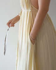 Person wearing a light yellow dress holding a decorative object against a plain background