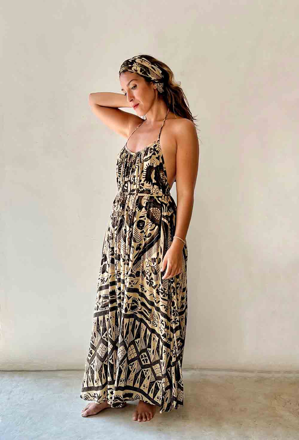 Woman wearing a patterned dress and headband against a plain background