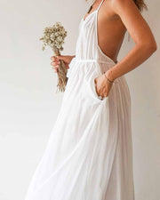 Woman in a white dress holding dried flowers against a plain background