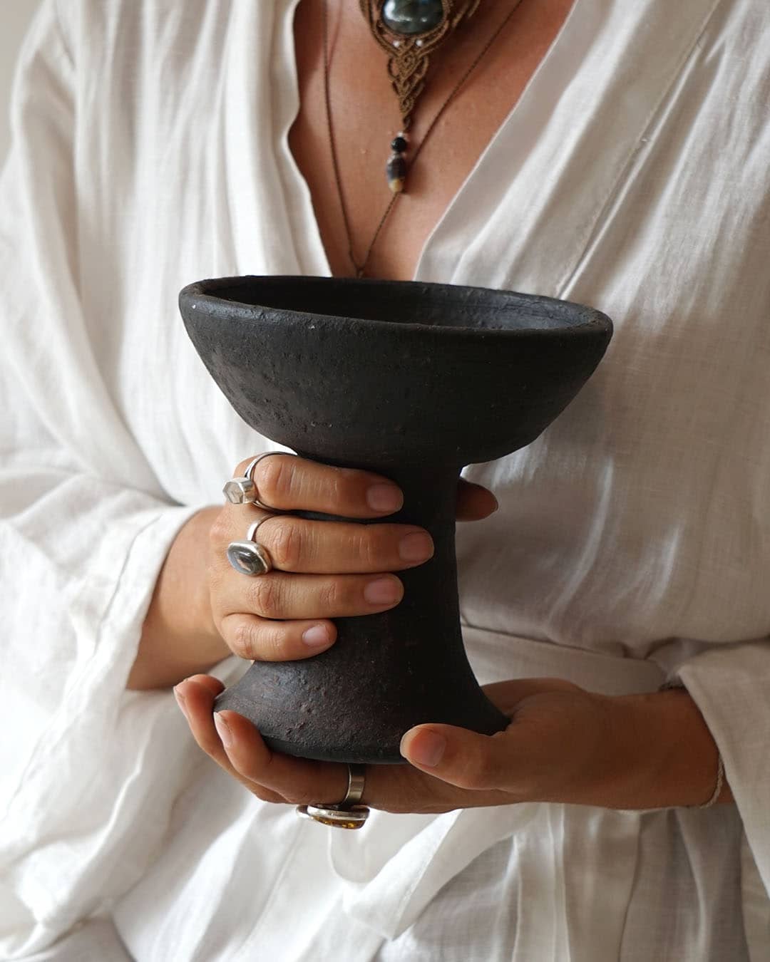Person holding a black ceramic cup against a white background