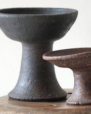 Two black ceramic bowls on a wooden surface with a white background
