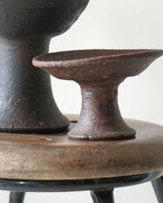 Close-up of a rustic metal stand with a textured surface on a neutral background
