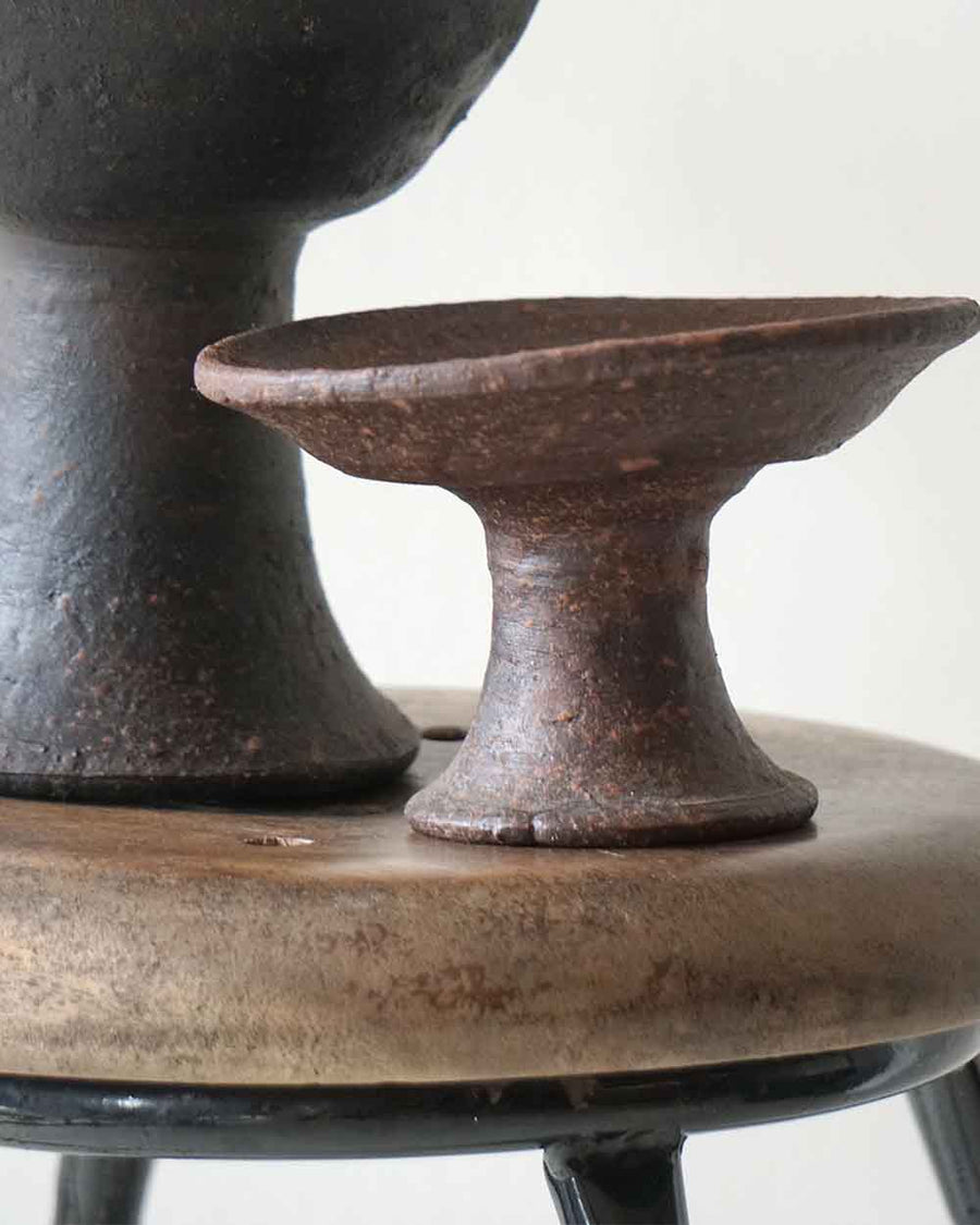 Close-up of a rustic metal stand with a textured surface on a neutral background