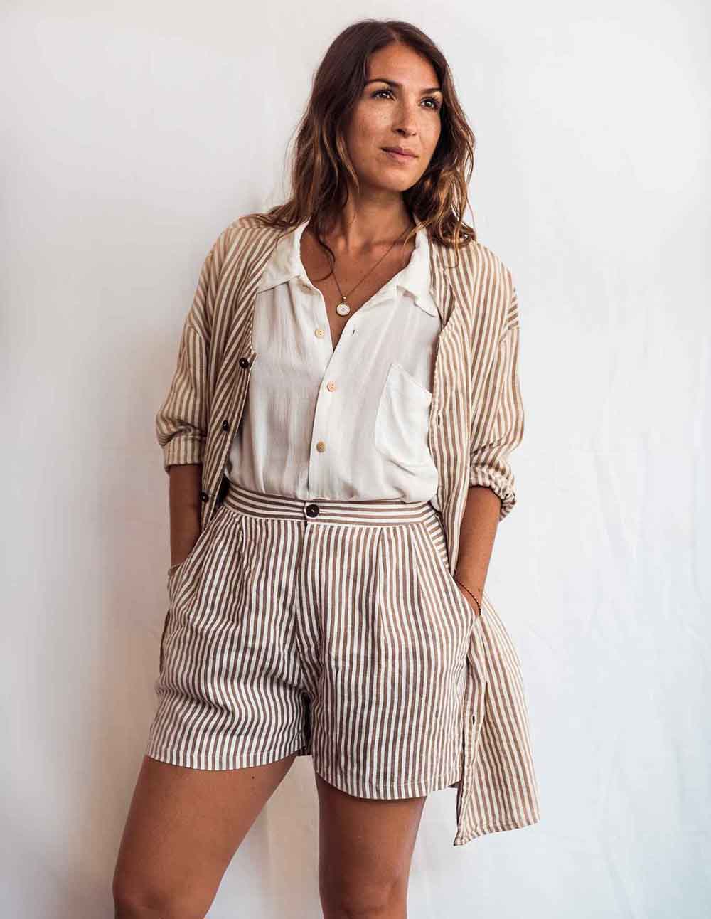 Woman wearing a striped outfit with a white shirt and shorts against a plain background