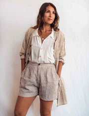 Woman wearing a striped outfit with a white shirt and shorts against a plain background