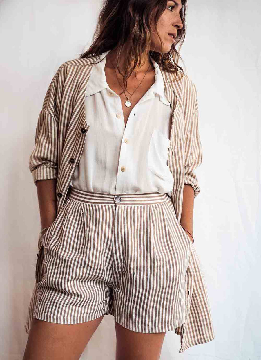 Woman wearing a striped shirt and shorts set against a plain background